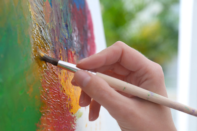 Photo of Artist painting on canvas with brush, closeup