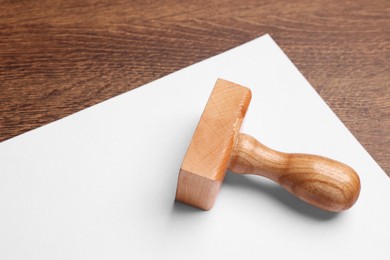 Photo of One stamp tool and sheet of paper on wooden table, closeup. Space for text