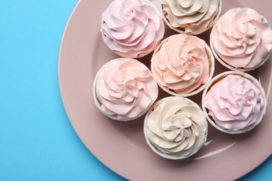 Photo of Plate with tasty cupcakes on light blue background, top view