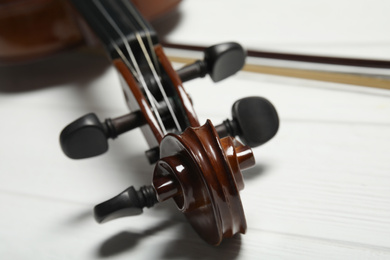 Photo of Classic violin on white wooden background, closeup
