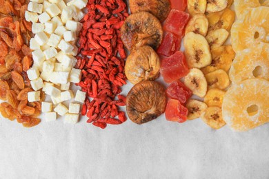 Photo of Different tasty dried fruits on paper, flat lay