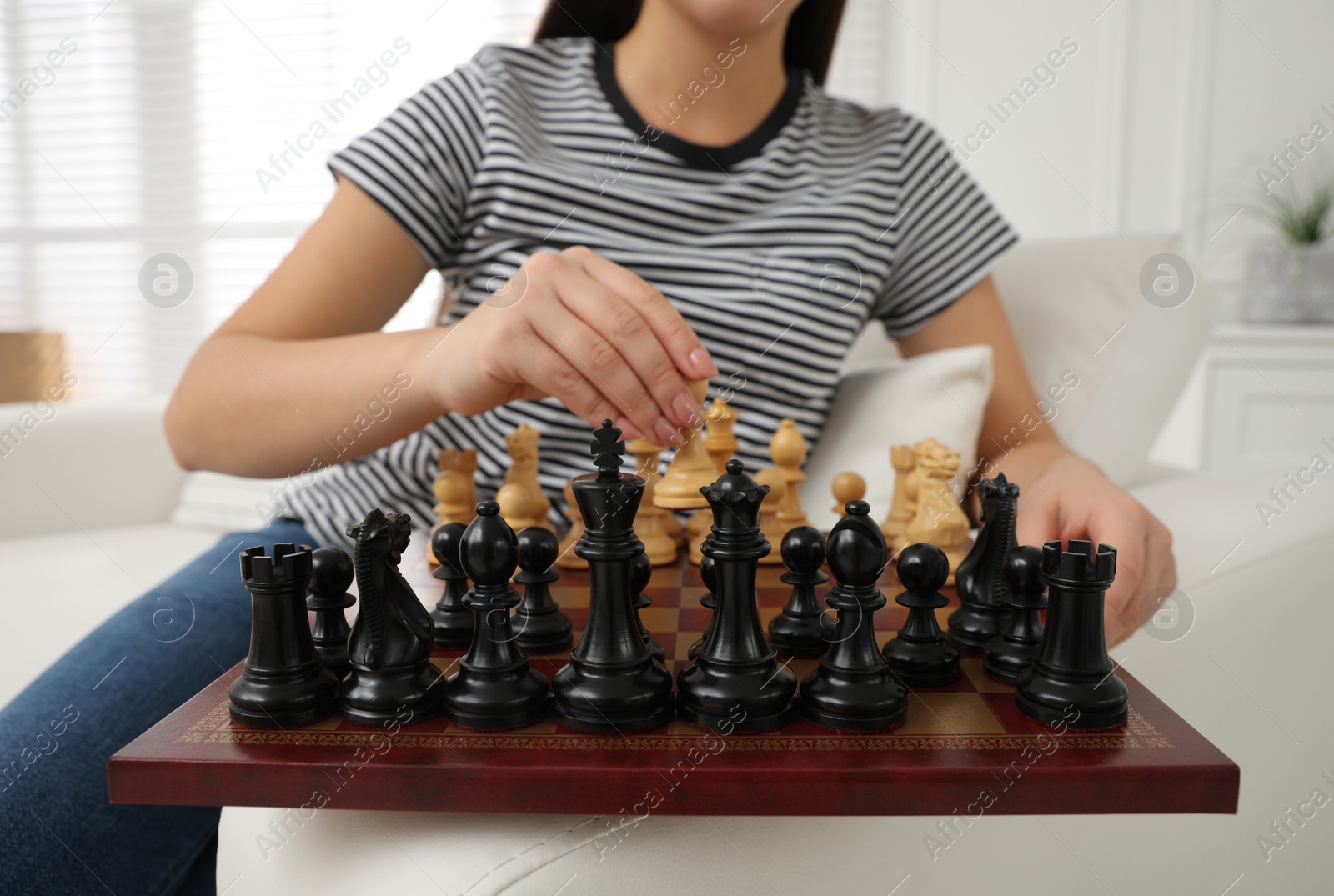 Photo of Woman playing chess on sofa at home, closeup