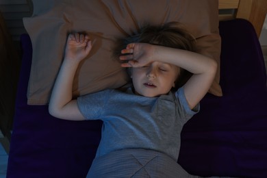 Photo of Little boy snoring while sleeping in bed at night, above view