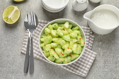 Photo of Delicious cucumber salad in bowl served on grey table, top view