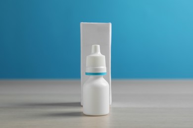 Photo of Bottle of nasal spray and package on white wooden table