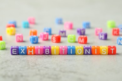 Photo of Word EXHIBITIONIST made with colorful cubes on light grey table