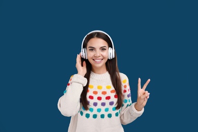 Photo of Young woman listening to music with headphones on dark blue background