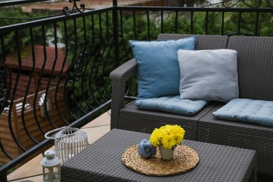 Photo of Different colorful pillows and yellow chrysanthemum flowers on rattan garden furniture outdoors