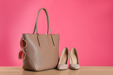 Photo of Stylish woman's bag, shoes and sunglasses on wooden table