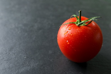 Photo of Fresh ripe tomato on black table, closeup. Space for text