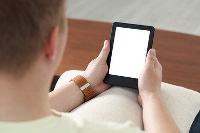 Photo of Man using e-book reader indoors, closeup view