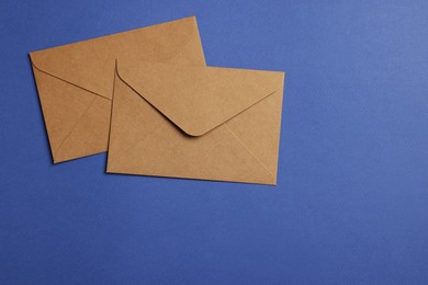 Photo of Envelopes made of parchment paper on blue background, flat lay. Space for text
