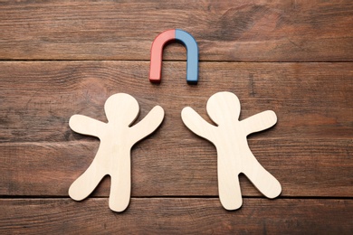 Photo of Magnet attracting people traffic on wooden background, top view. Marketing concept