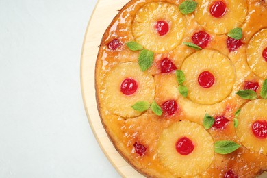 Photo of Tasty pineapple cake with cherries and mint on white table, top view. Space for text