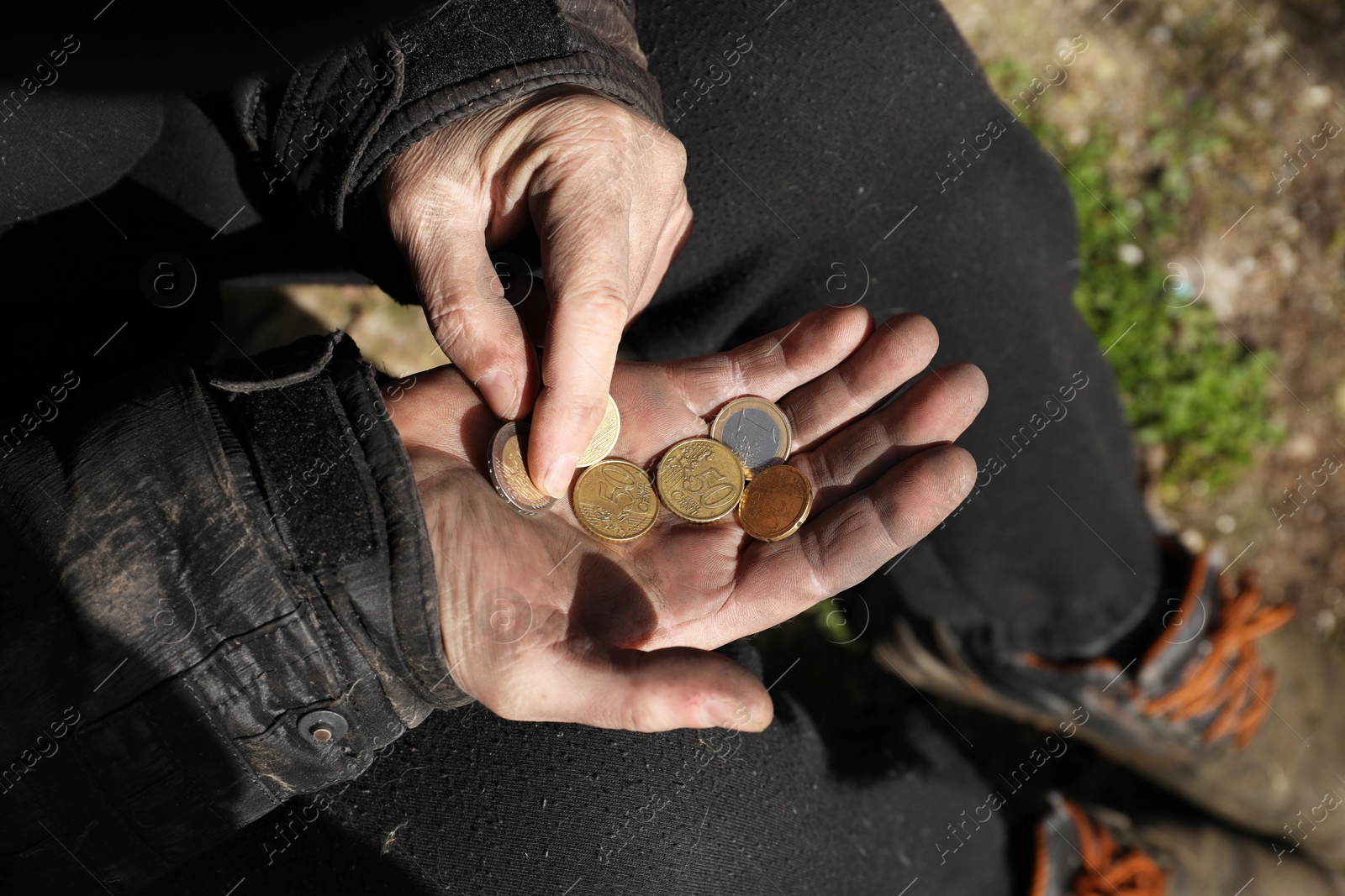 Photo of Poor homeless man holding coins outdoors, closeup