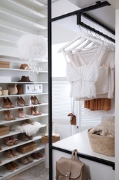 Photo of Dressing room interior with clothes rack and collectionstylish shoes