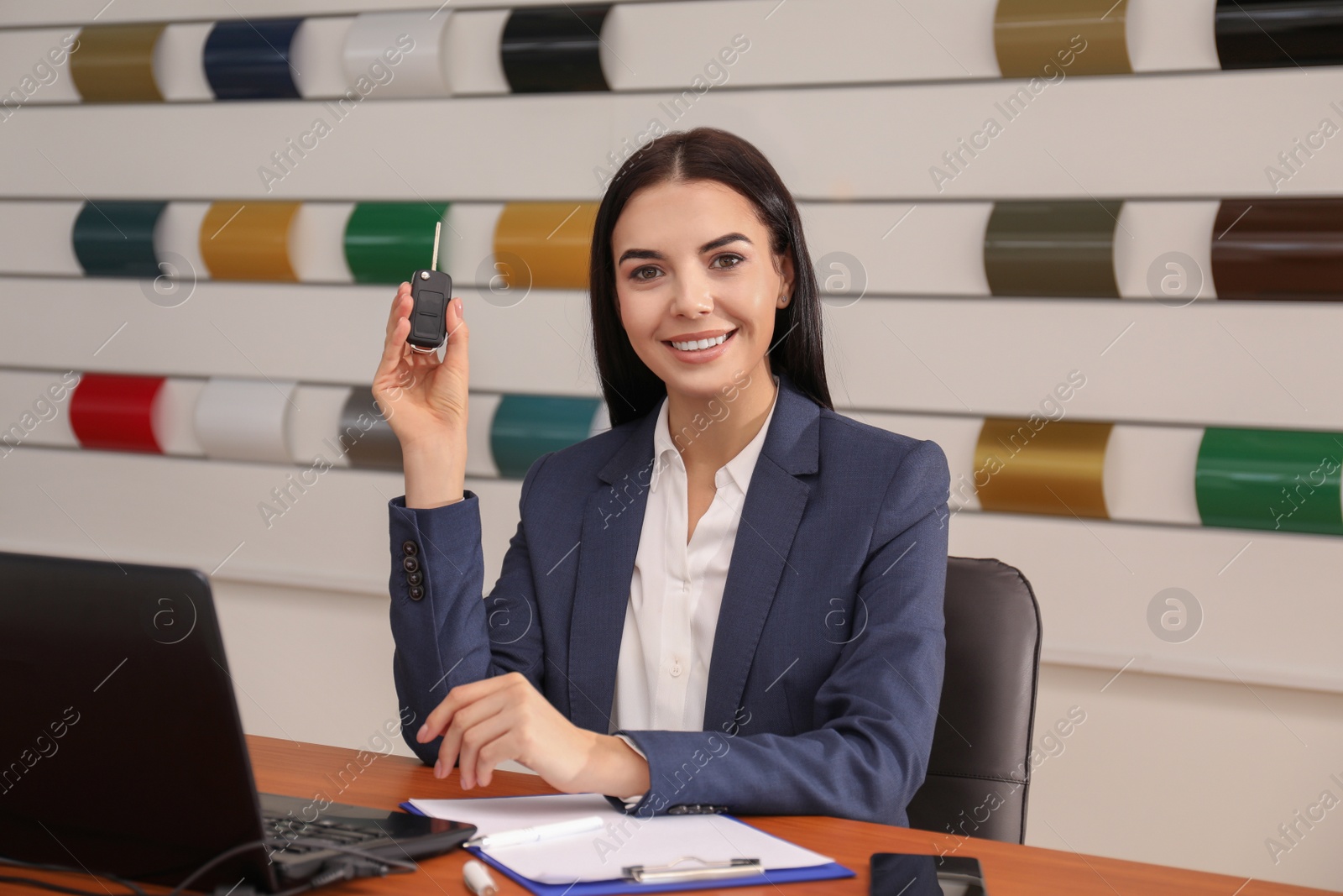 Photo of Saleswoman with car key at desk in office