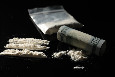 Photo of Drug addiction. Cocaine and rolled dollar banknote on black table, closeup
