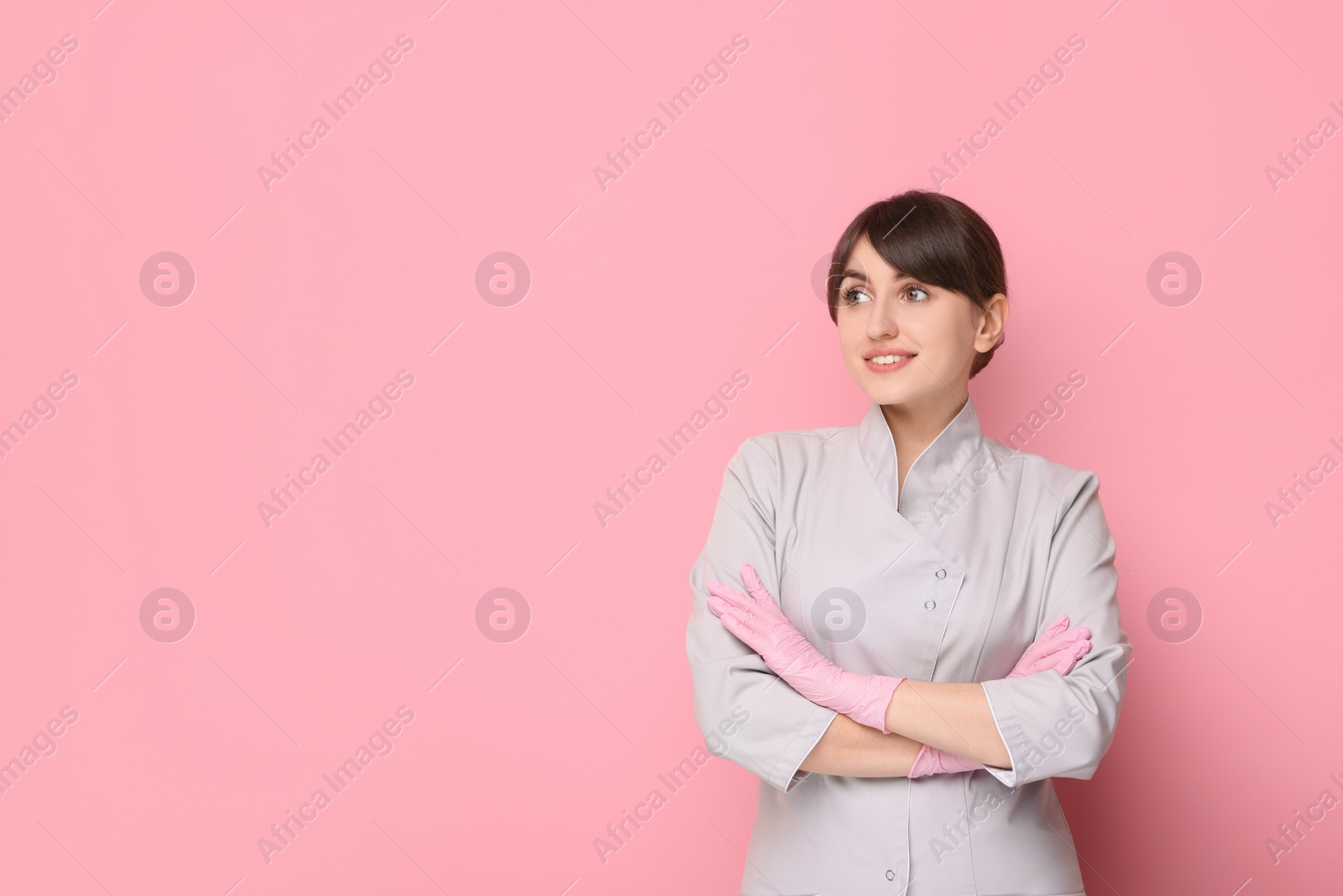 Photo of Cosmetologist in medical uniform on pink background, space for text