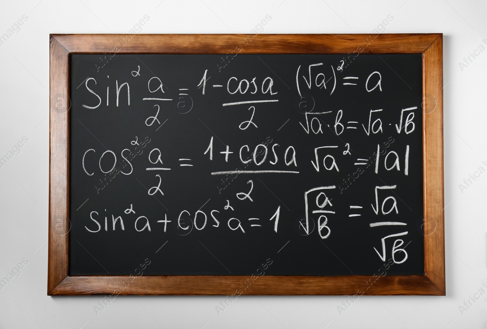 Photo of Blackboard with different mathematical formulas written with chalk on white wall