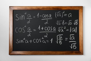 Blackboard with different mathematical formulas written with chalk on white wall