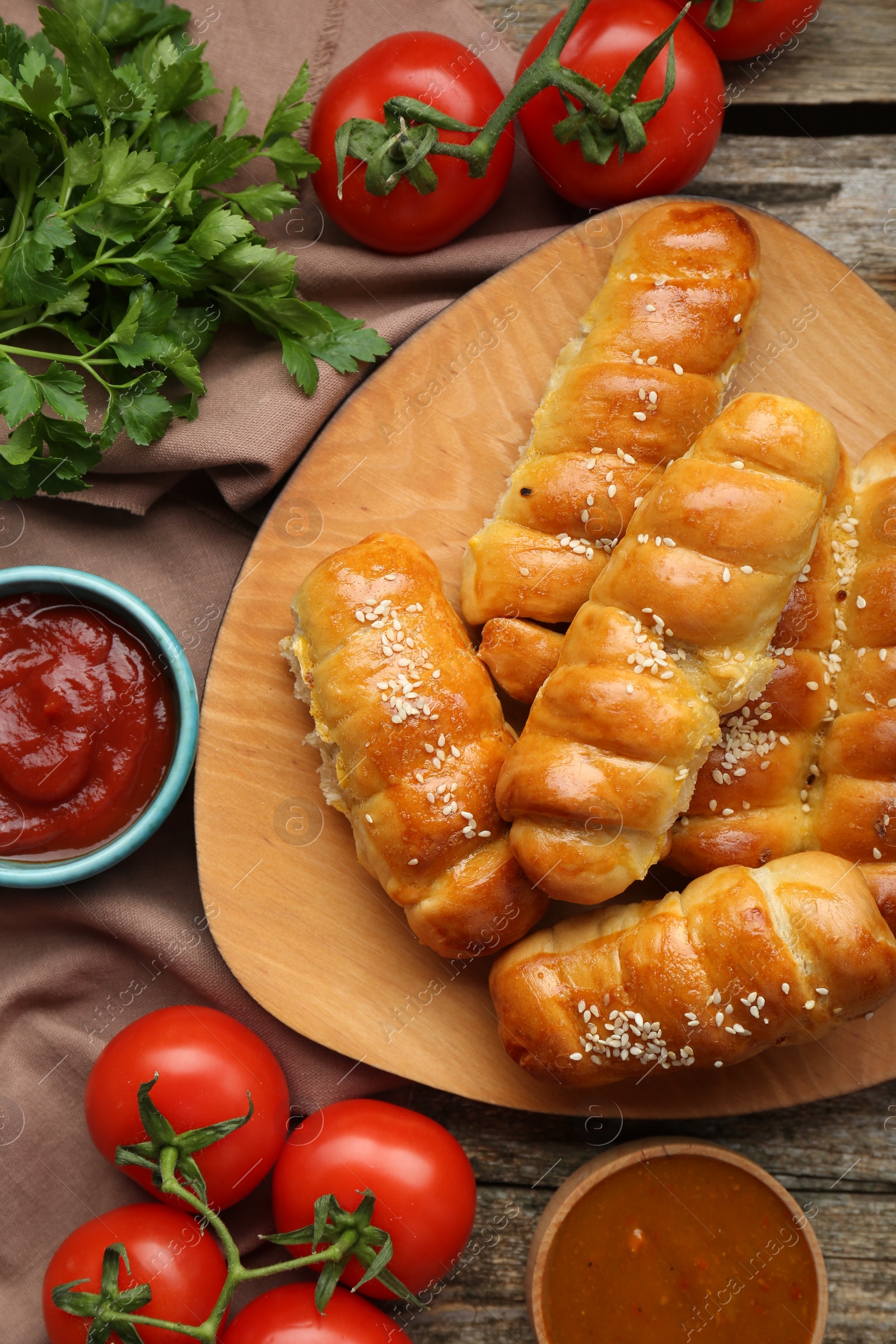 Photo of Delicious sausage rolls and ingredients on wooden table, flat lay