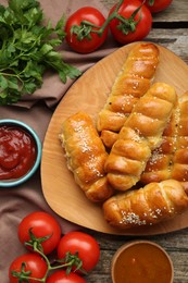 Photo of Delicious sausage rolls and ingredients on wooden table, flat lay