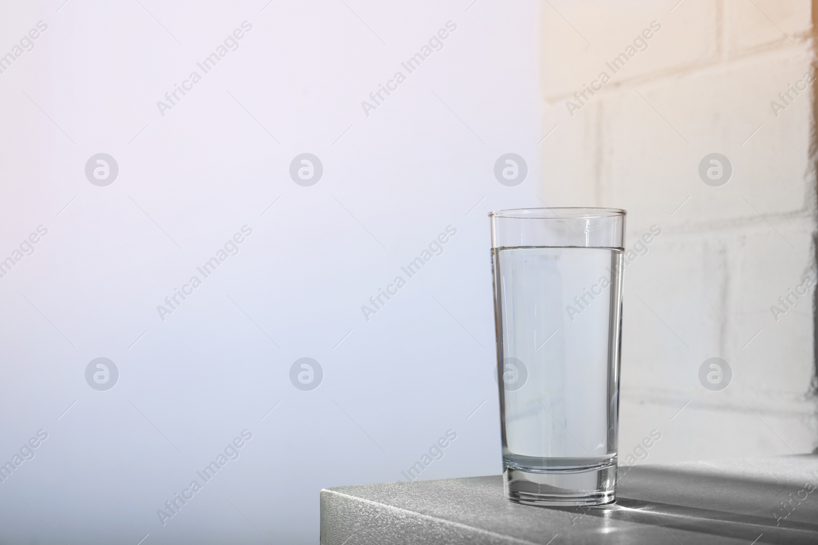 Photo of Glass of water on table against light background. Space for text