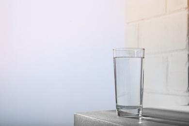 Glass of water on table against light background. Space for text