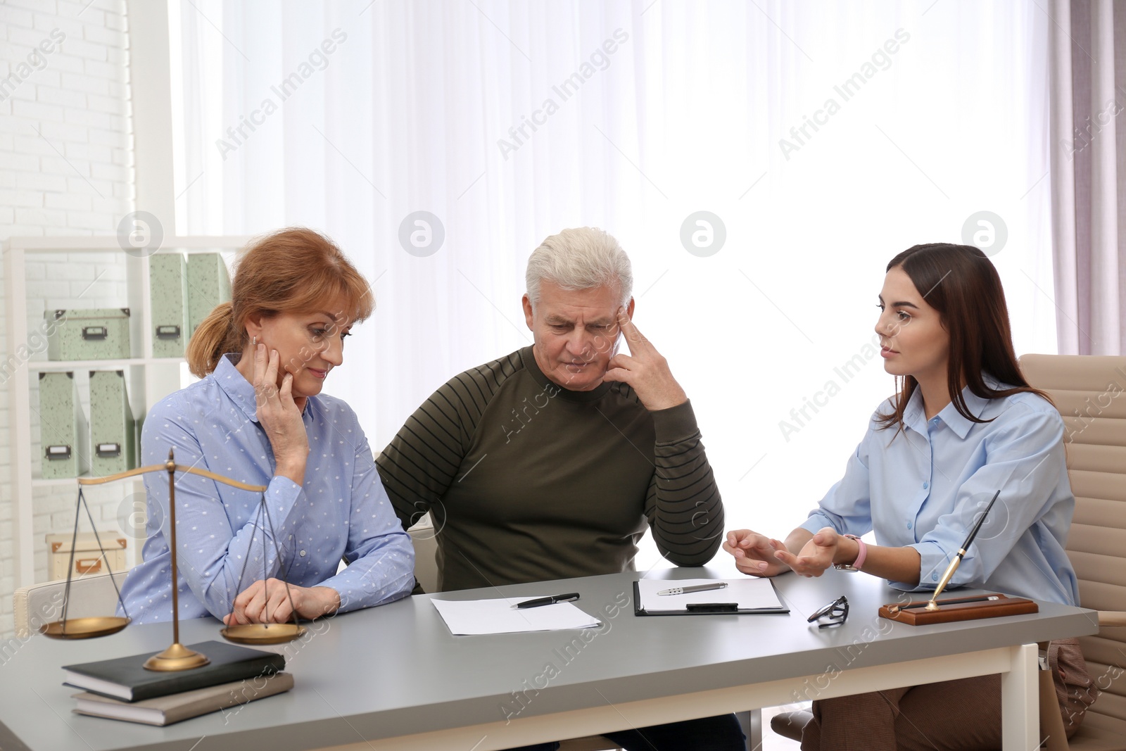 Photo of Young lawyer consulting senior couple in office