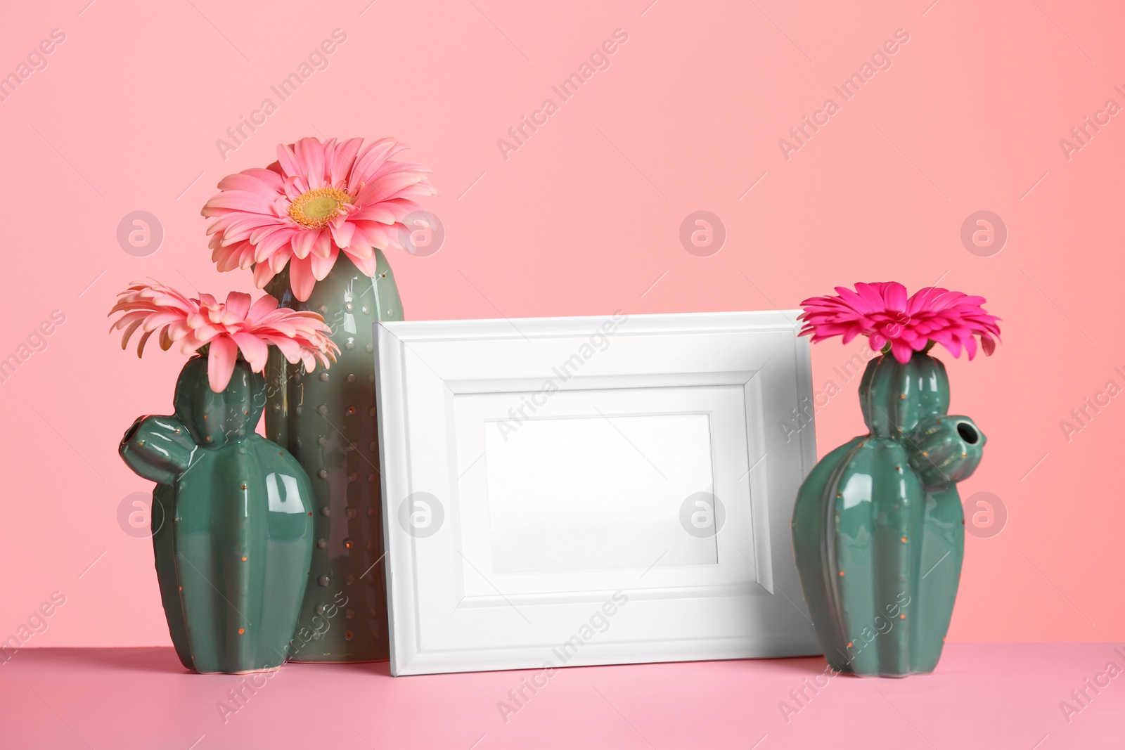 Photo of Decorative cacti, flowers and photo frame on table against color background, space for text. International Women's Day