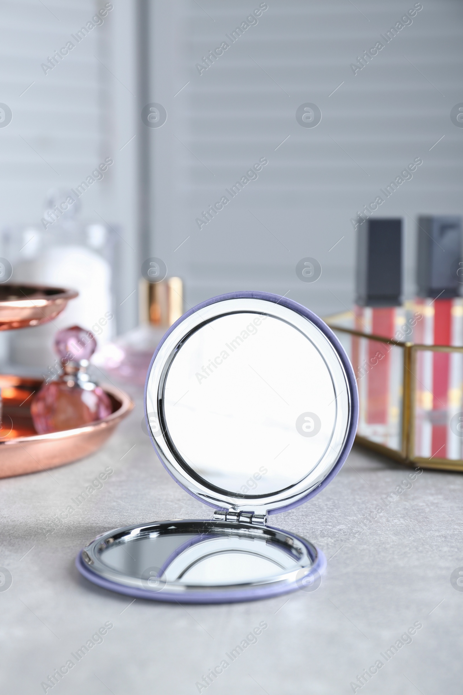 Photo of Stylish pocket mirror and cosmetic products on grey table