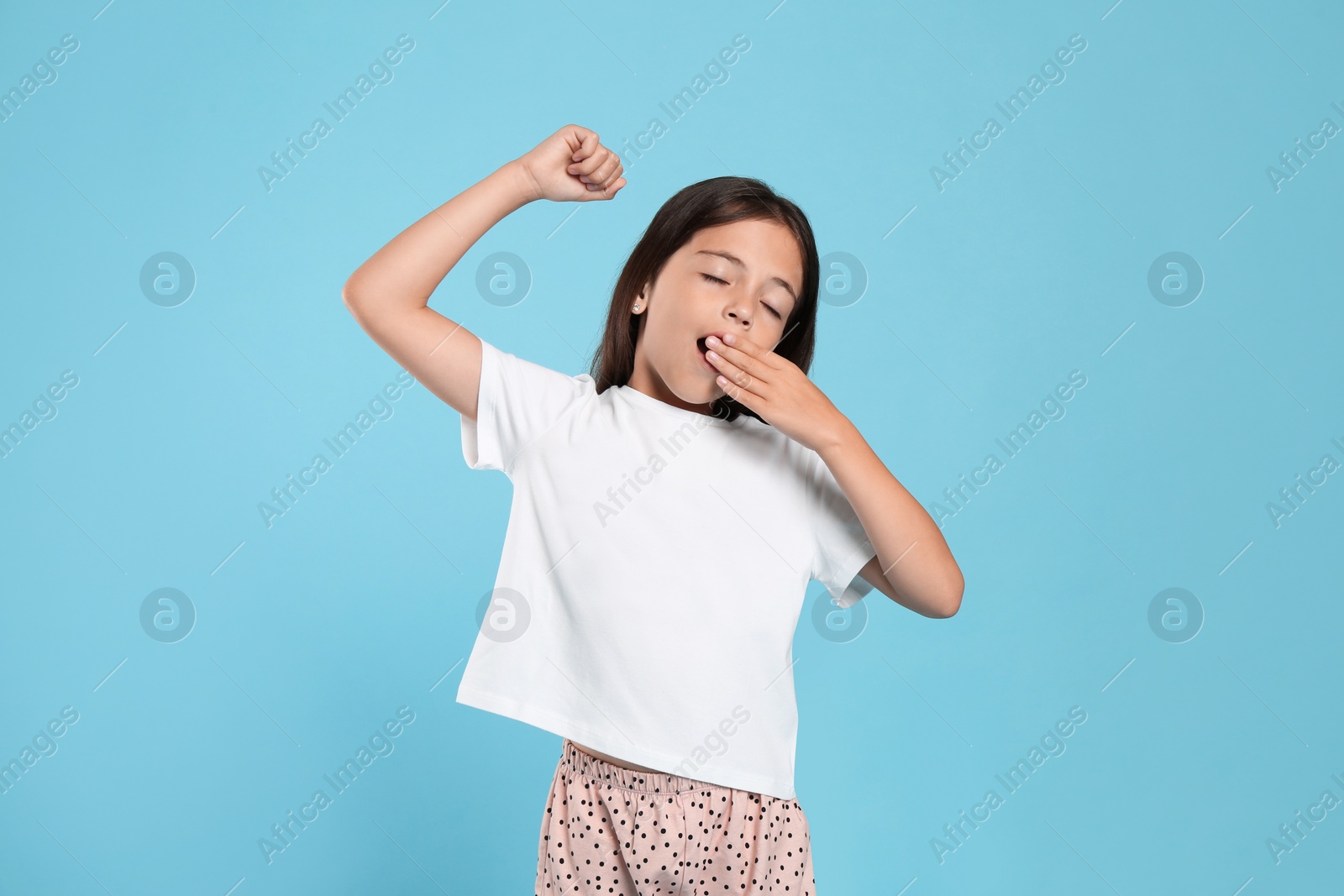 Photo of Cute girl wearing pajamas on light blue background