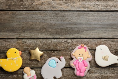 Cute tasty cookies of different shapes and space for text on wooden table, flat lay. Baby shower party