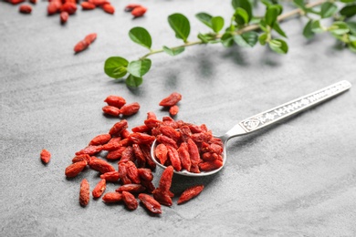 Photo of Spoon and dried goji berries on grey table. Healthy superfood