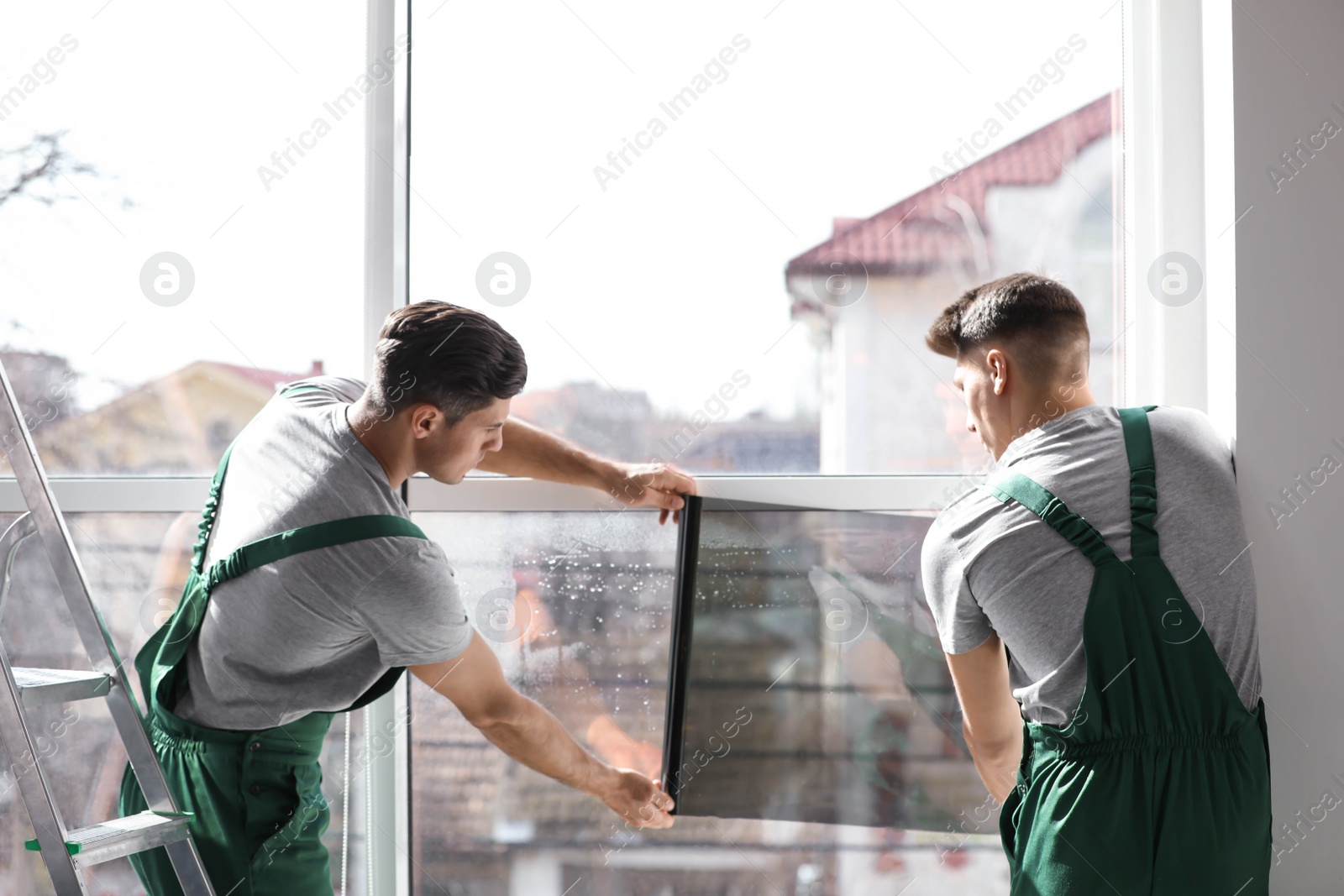 Photo of Professional workers tinting window with foil indoors