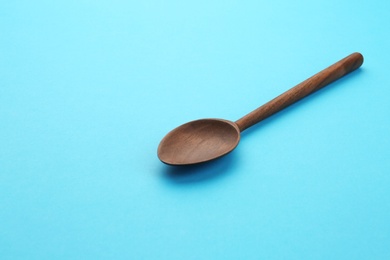 Photo of Clean empty wooden spoon on blue background, space for text