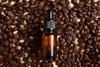 Bottle of organic cosmetic product and coffee beans on beige background, flat lay