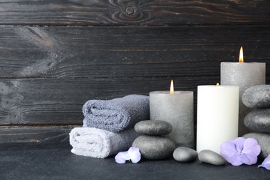 Photo of Composition with zen stones, towels and candles on table against wooden background. Space for text