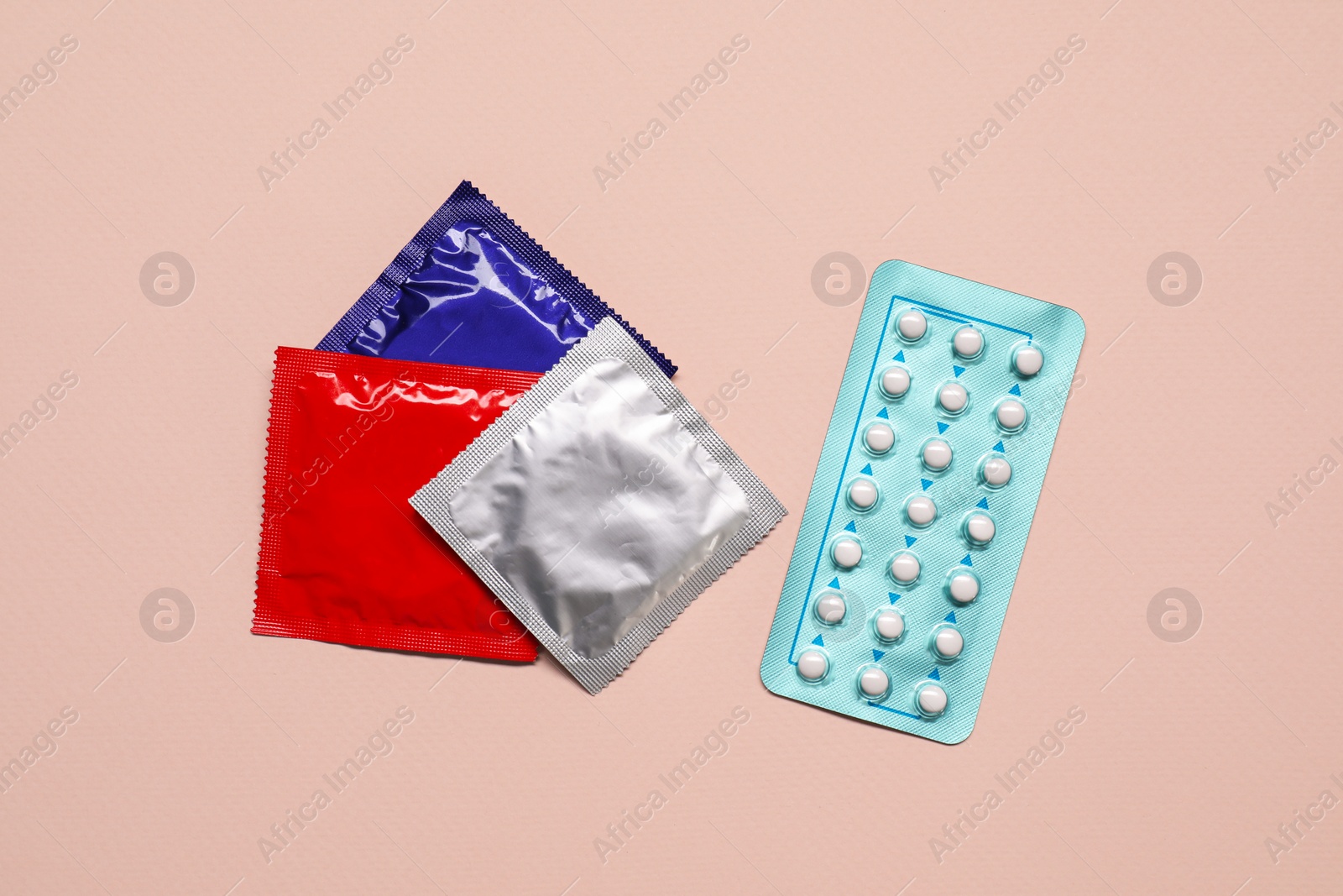 Photo of Contraception choice. Pills and condoms on beige background, flat lay