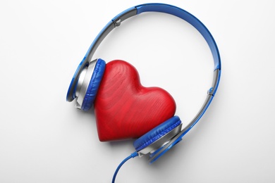 Photo of Decorative heart and modern headphones on white background, top view