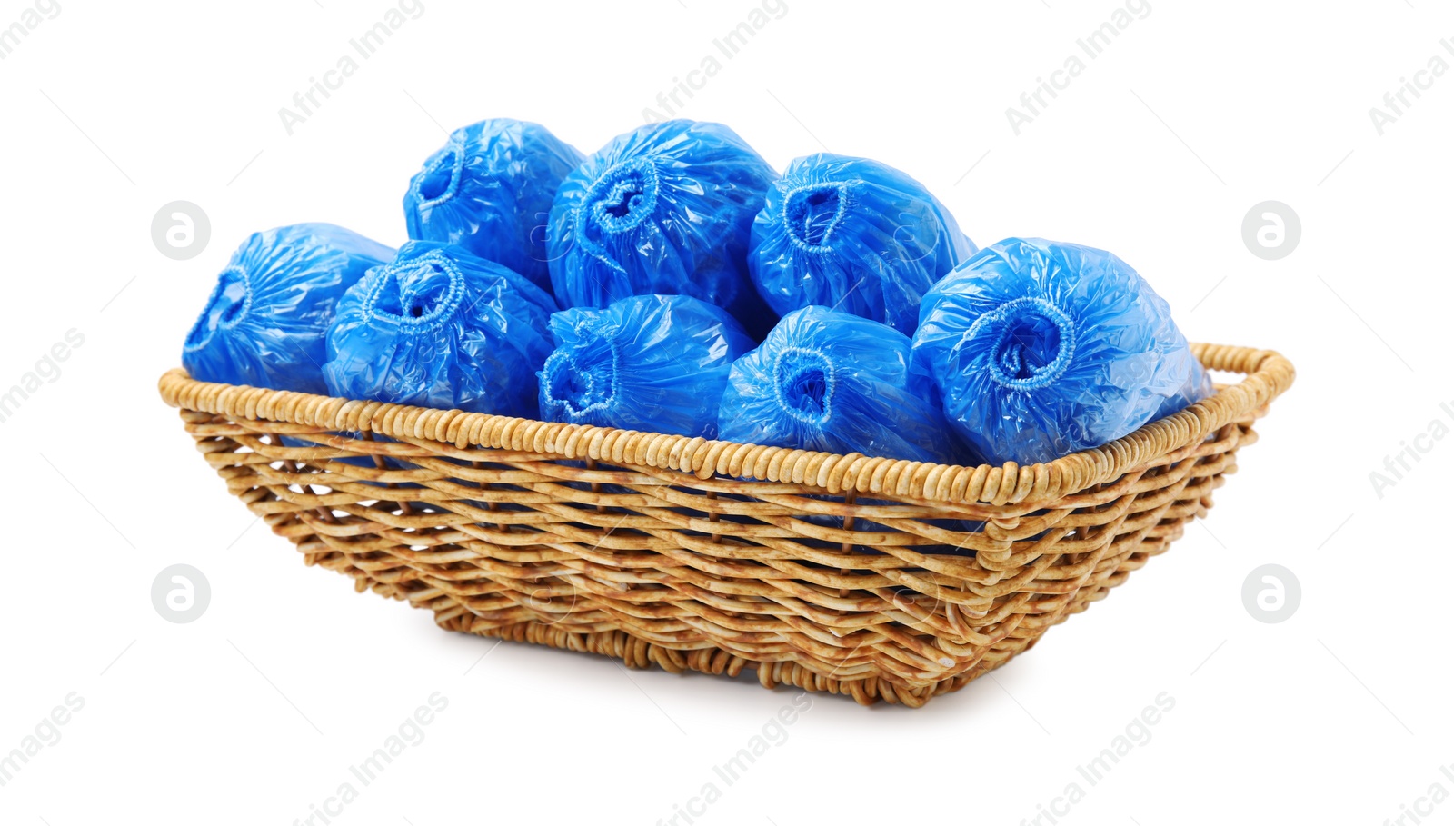 Photo of Rolled blue shoe covers in wicker basket isolated on white