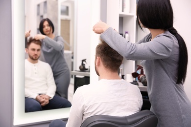 Professional female hairdresser working with client in salon