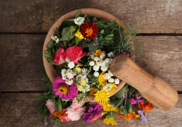 Photo of Mortar, pestle and different flowers on wooden table, top view