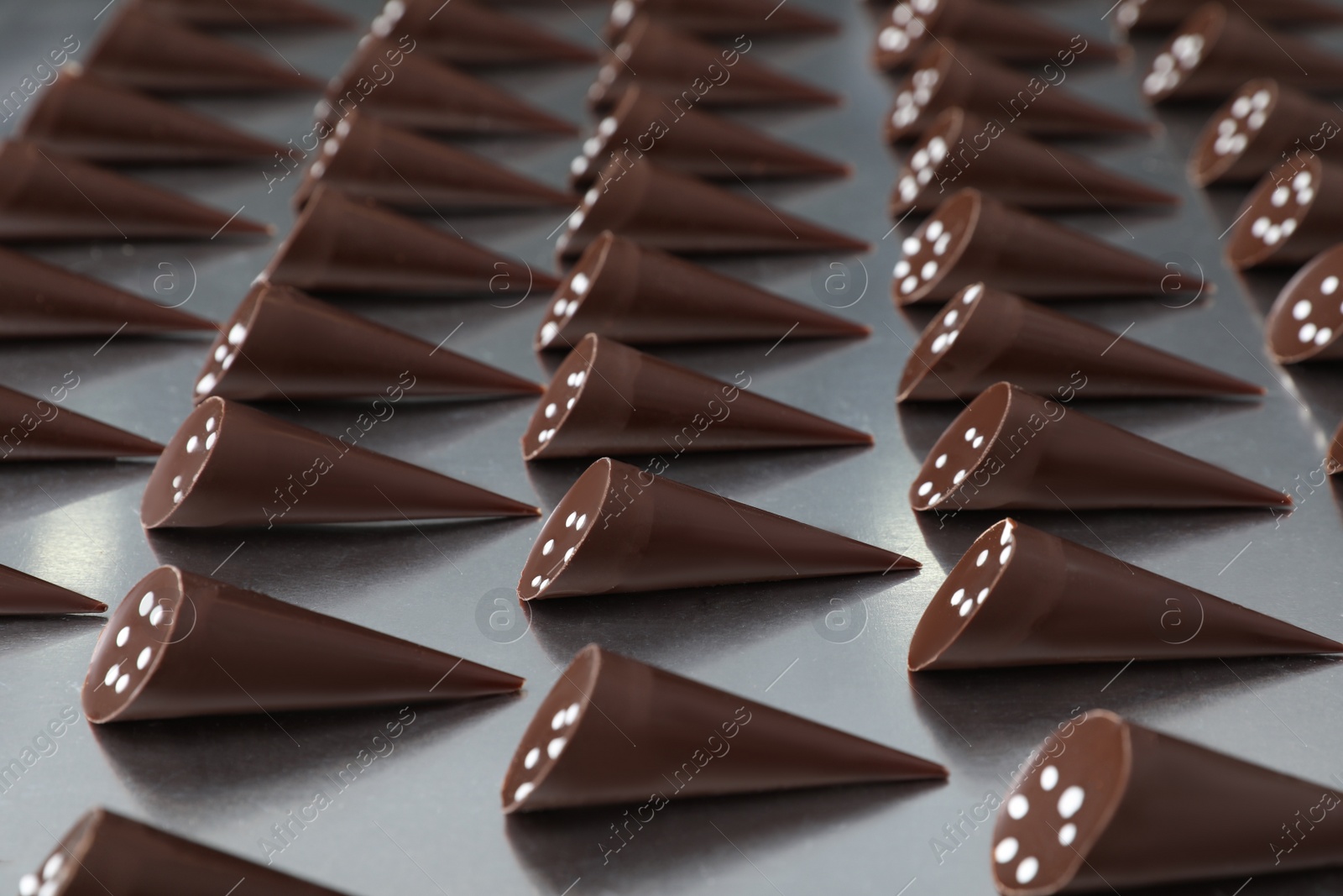 Photo of Many tasty chocolate candies on metal surface. Production line