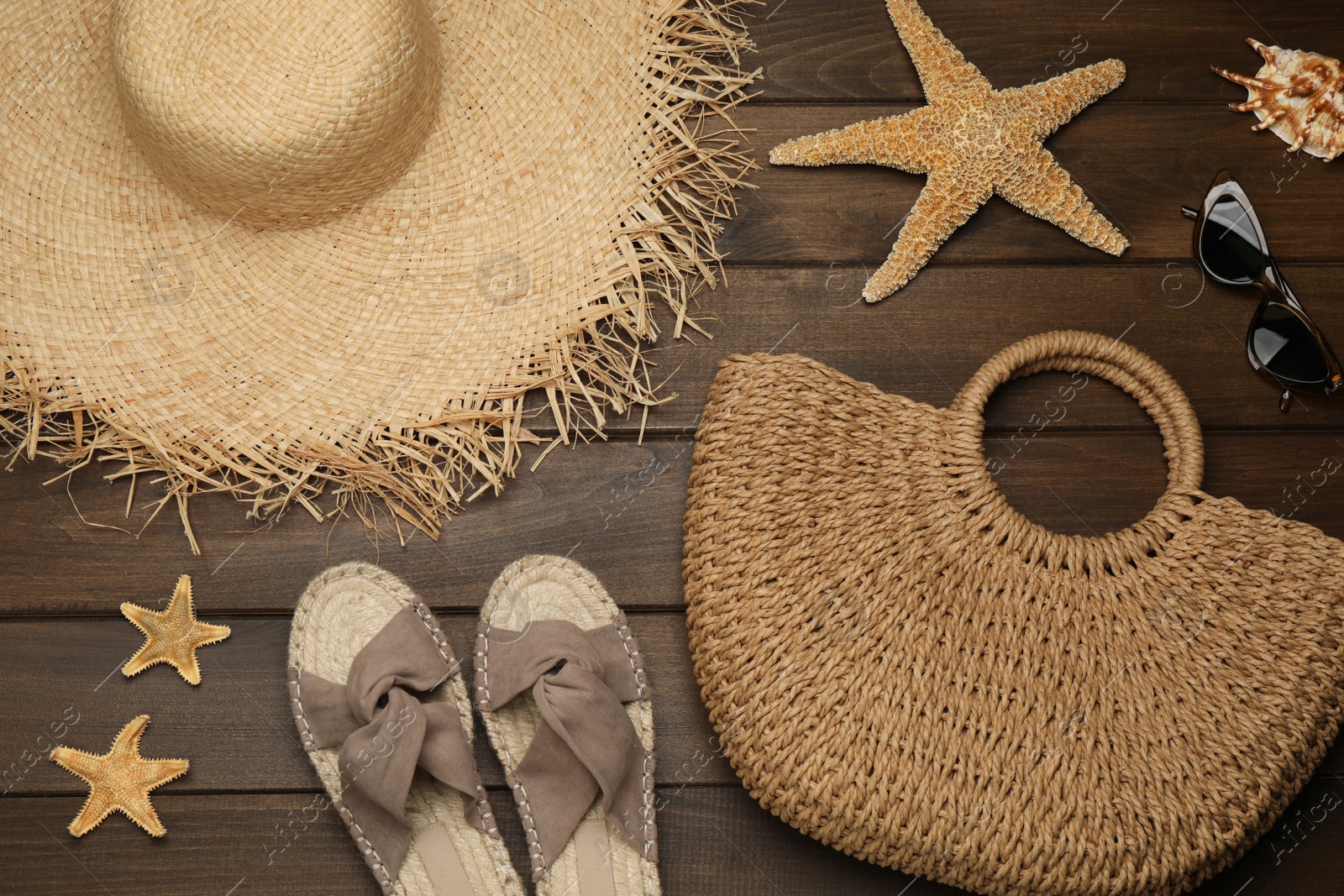 Photo of Stylish bag and beach accessories on wooden background, flat lay