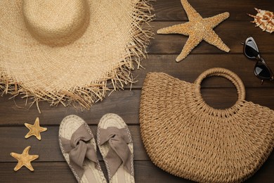 Stylish bag and beach accessories on wooden background, flat lay