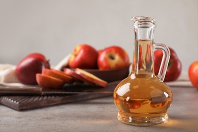 Photo of Composition with jug of apple vinegar on table. Space for text