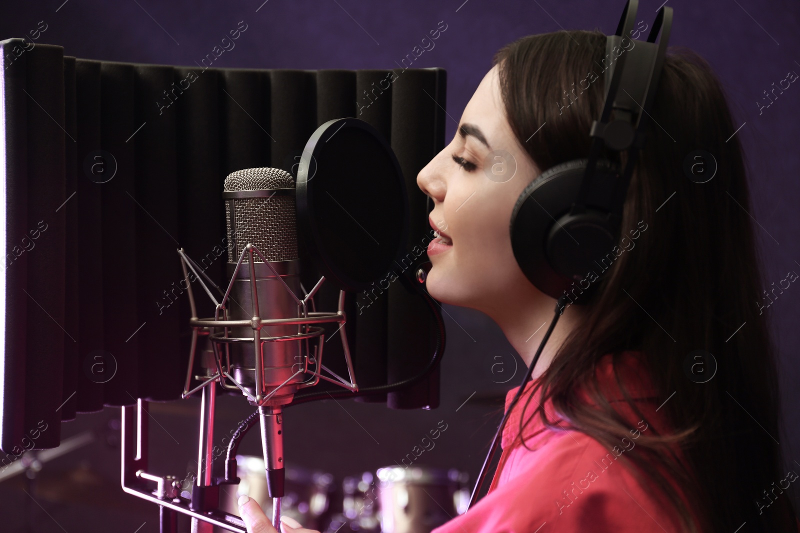 Photo of Young singer with microphone recording song in studio