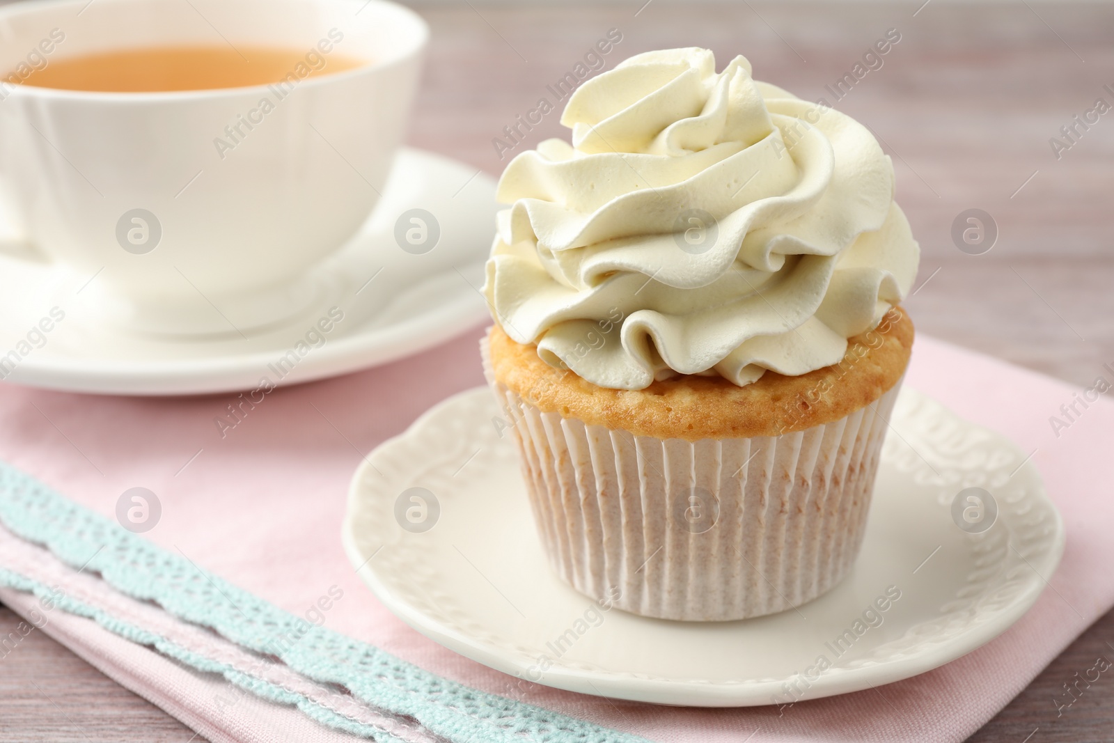 Photo of Tasty cupcake with vanilla cream on pink wooden table, closeup